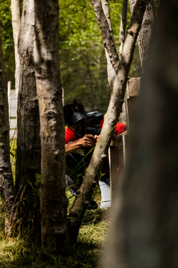 Joueur paintball embusqué entre les arbres
